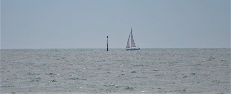 A sail boat next to the Mixon Marker, off East Beach, Selsey