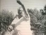 A black and white image of Sir Patrick Moore wearing cricket whites and in mid bowl action