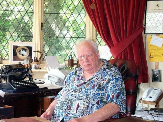 Sir Patrick Moore sat at a busy desk which incudes an old typewriter