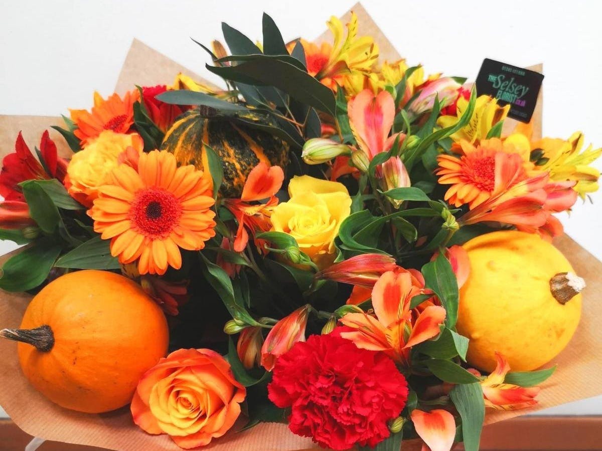 Delectable display of orange and yellow flowers finished off with a pair of yellow and orange squashes