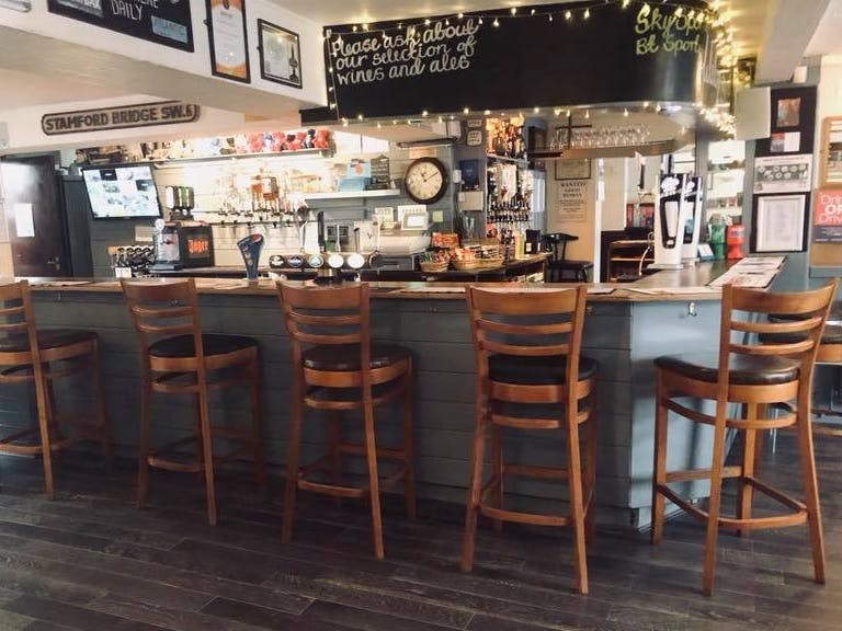 Welcoming bar area of the Nepune Pub with backed bar stools. 