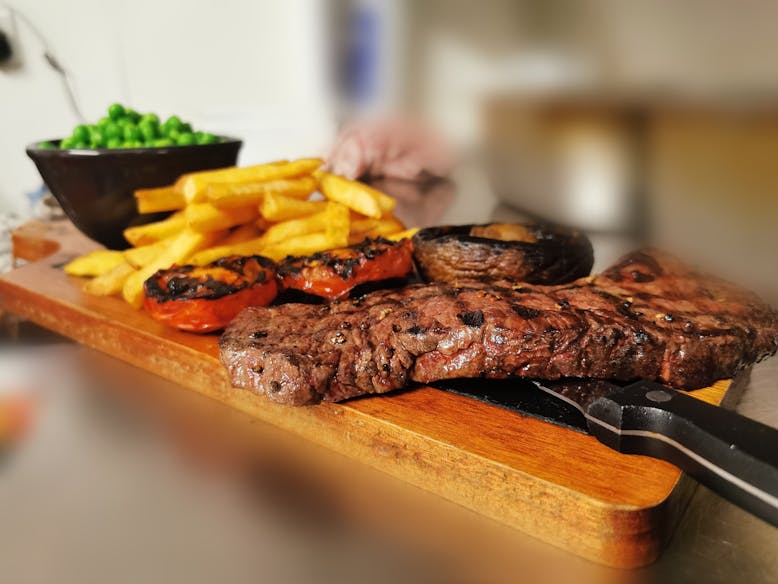 Steak at The Crown Inn, courtesy of The Crown Inn A platter of grilled steak, grilled tomatoes, mushroom, chips and peas served at The Crown Inn