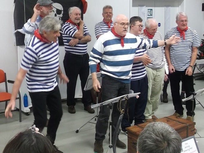 The Selsey Shantymen performing dressed in their blue and white striped shirts and red scarfs