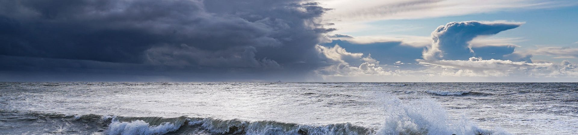 The waves hitting rocks and the clouds take on a majestic formation in the sky