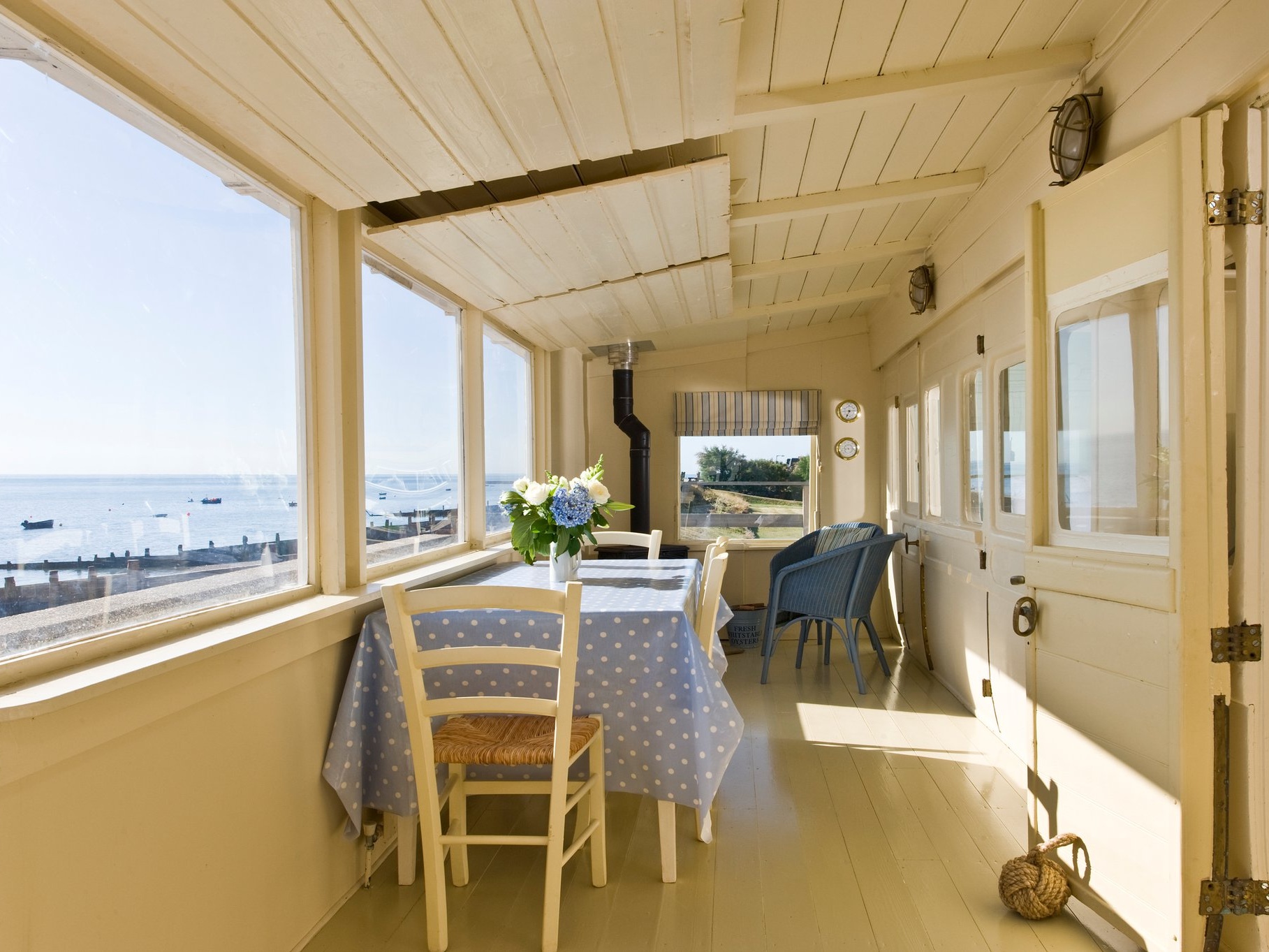 Seabank home made up of two railway carriages in the image can be seen to the right the railway carriage doors.  To the left the main seating area looking out on large windows at the seascape of Selsey