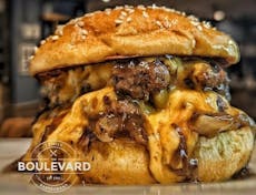 Image of a burger with melted cheese with the logo of the Boulevard Selsey Restaurant