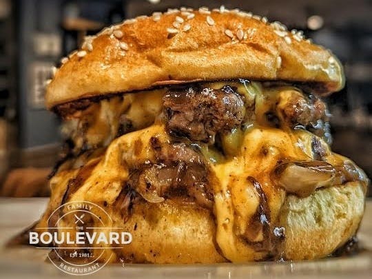 Image of a burger with melted cheese with the logo of the Boulevard Selsey Restaurant