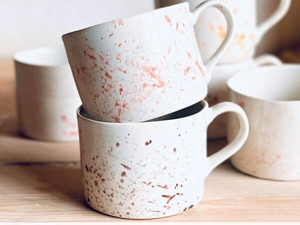Two stacked porcelain mugs with splatter design