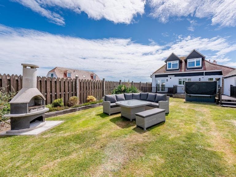 Photograph of a two storey house taken from the back with garden furniture and a pixxa oven in the foreground