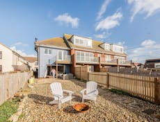 Photogrph of the back of a beachside property with two adirondack style chairs in the gravel garden