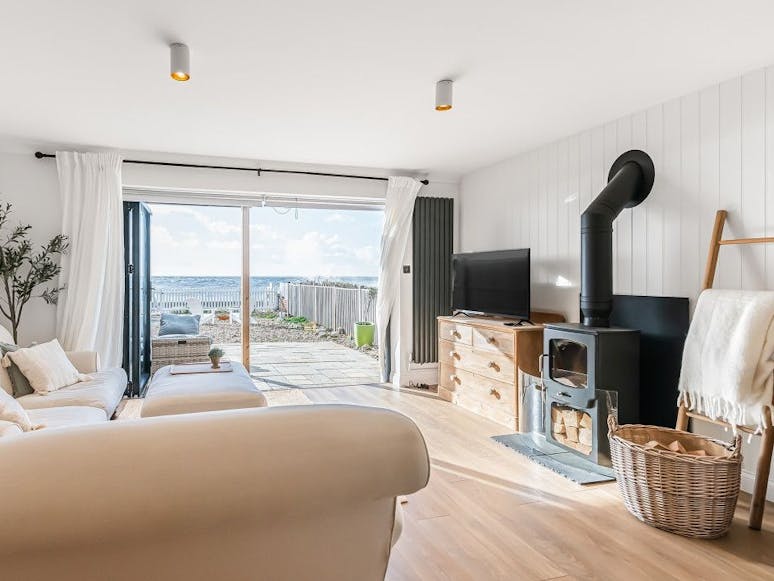 Seaspray Internal photograph of a property with bifold doors leading out to the beach, a log burning fire, wooden floors and neutral decorations