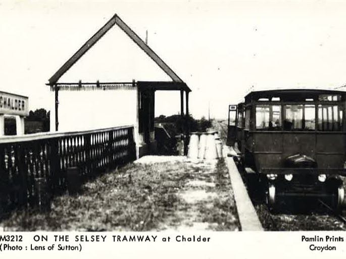 Black and white image showing a tram stationary at Calder station stop