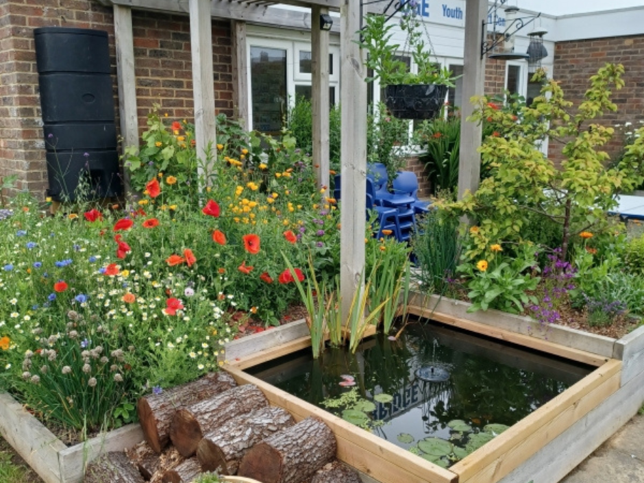 Photograph of The Hidden garden with flowers in bloom and a small, square pond