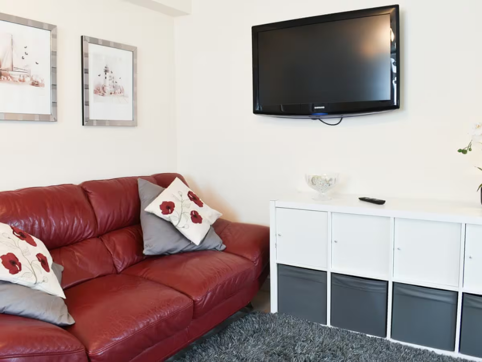 Photograph of a living room with sofa and wall mounted television
