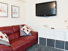 Photograph of a living room with sofa and wall mounted television