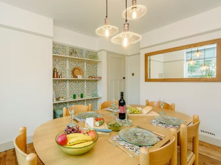 Photograph of a dining room with table laid with wine, fruit,cheese and bread