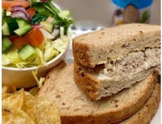 Photograph of a crab sandwich with side salad and crisps