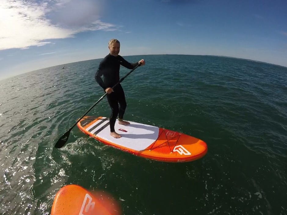 Photograph of a person standing up on a paddle board in water