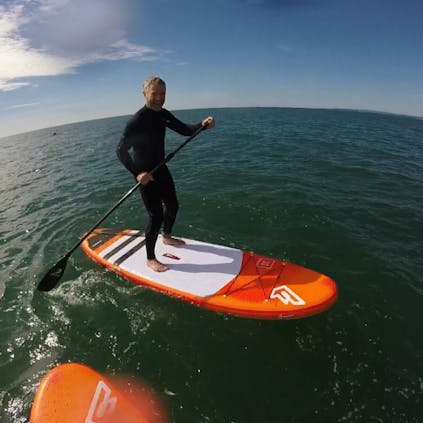 Photograph of a person standing up on a paddle board in water