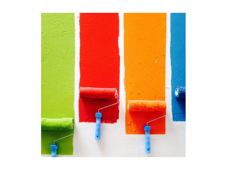 Photograph of 4 different colours being applied by paint rollers