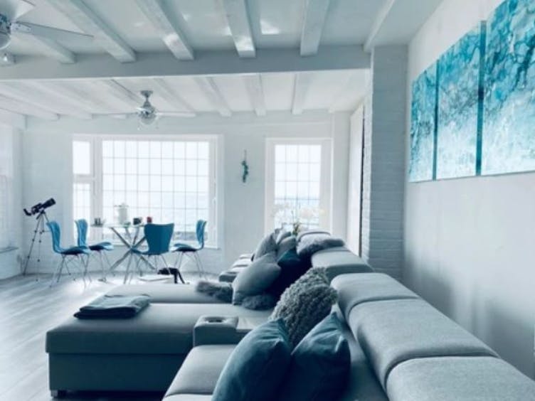 Photograph of a modern furnished living room with sofa, table, chairs and a telescope