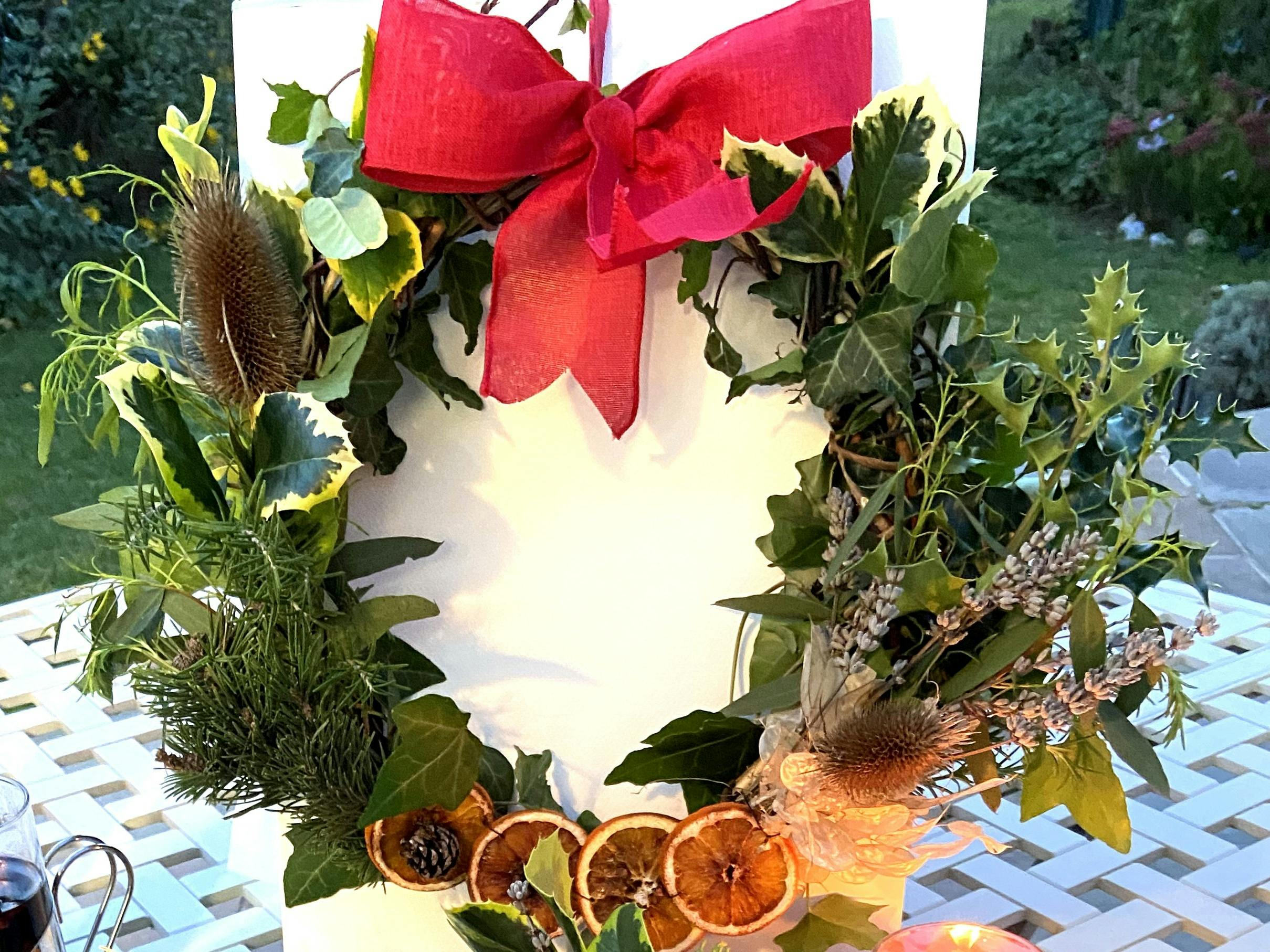 Chrismas wreath with dried orange slices, red ribbon and thistle tufts