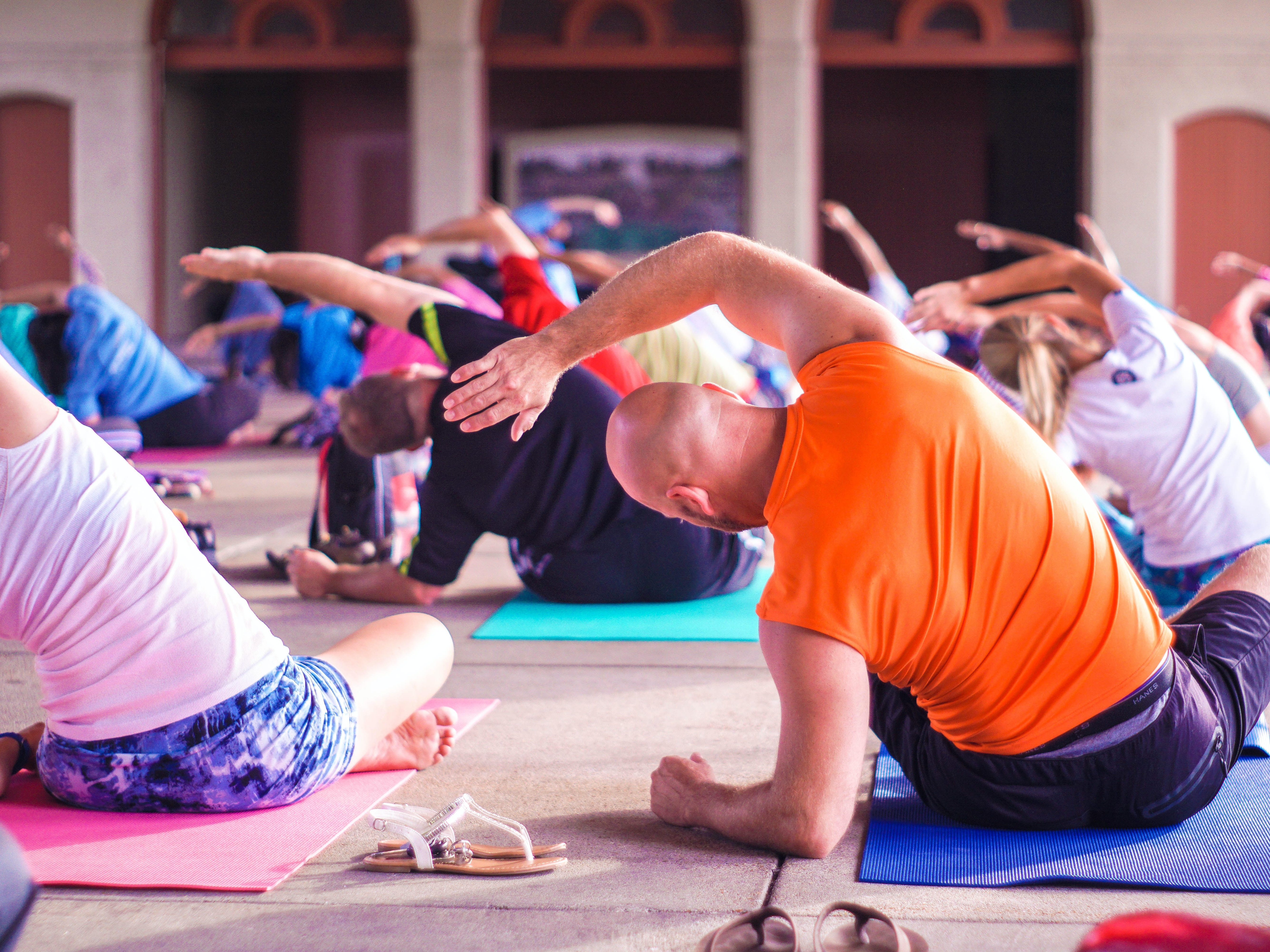 A group taking part in a yoga session all sat on yoga mats reaching over to their left