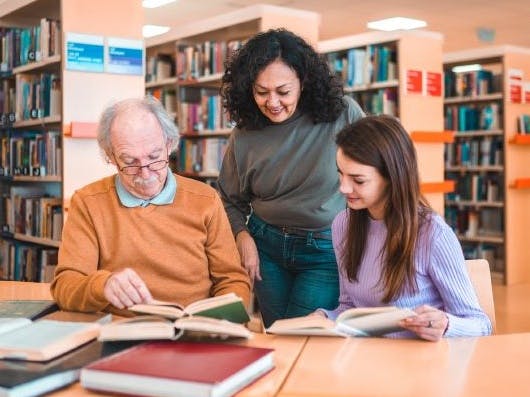 Three people reading at a library