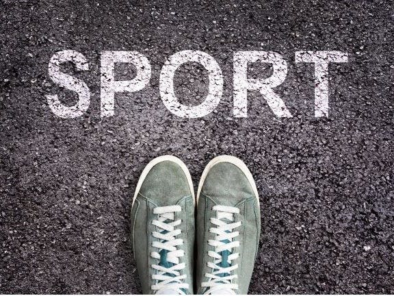 a pair of shoes with the word SPORT stencilled in white on tarmac, above the shoes
