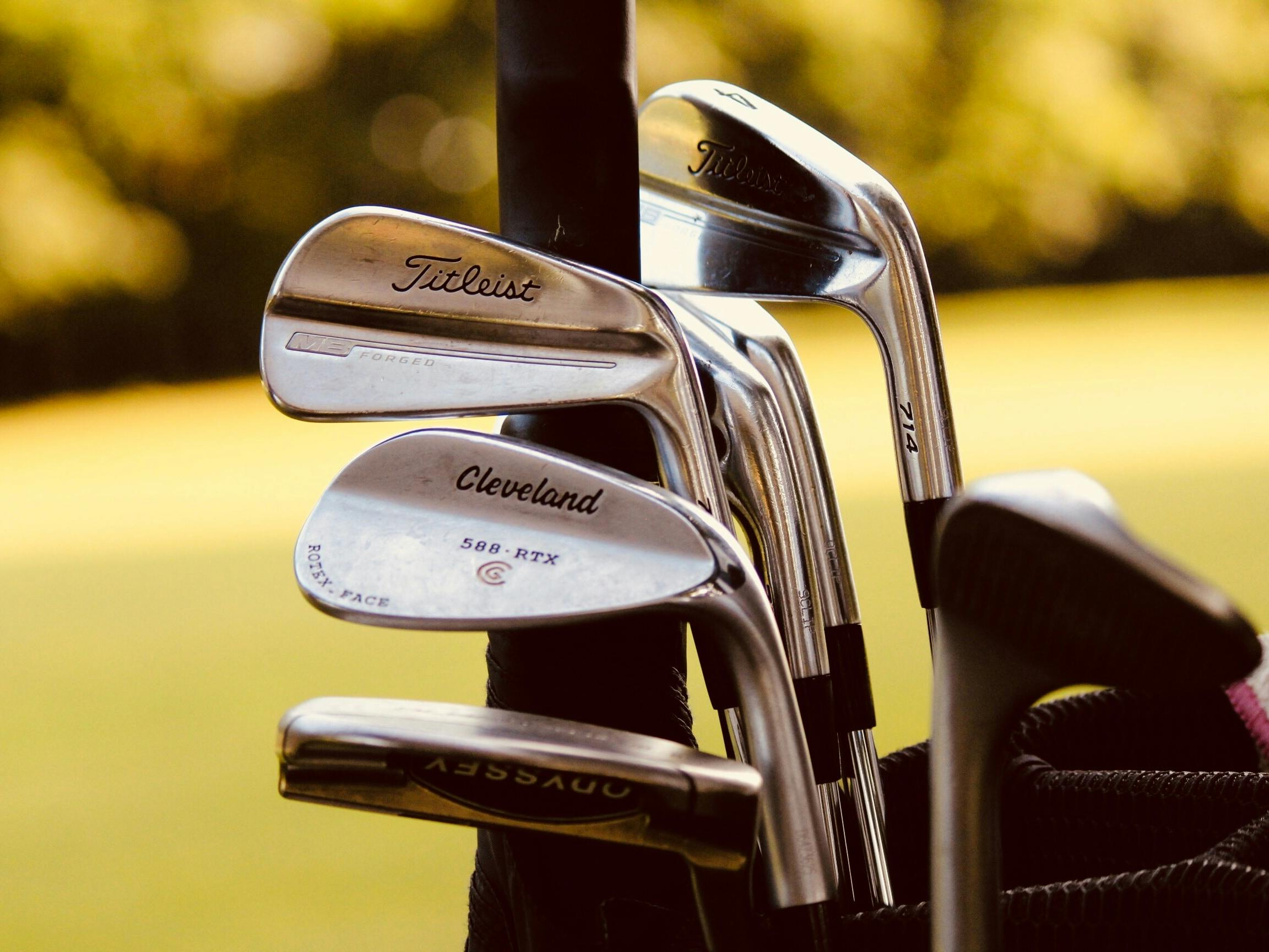 Close up image of golf clubs with a green background which is out of focus