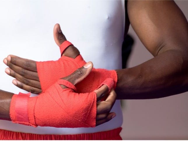 Image of a person's hands with red boxing bindings on