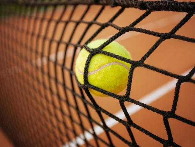 Photograph of a tennis ball hitting a net