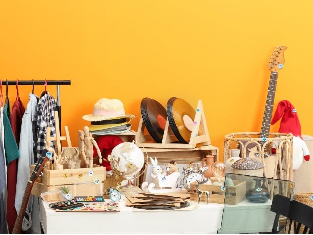 Photograph of a jumble sale with old lps, guitar, children's toys old clothes and hats and such