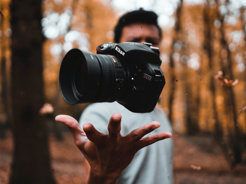 Photography in nature, courtesy of Reinhart Julian on Unsplash photograph of a person catching a camera  with a woodland back drop