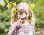 Photograph of girl with magnifying glass up close to her face