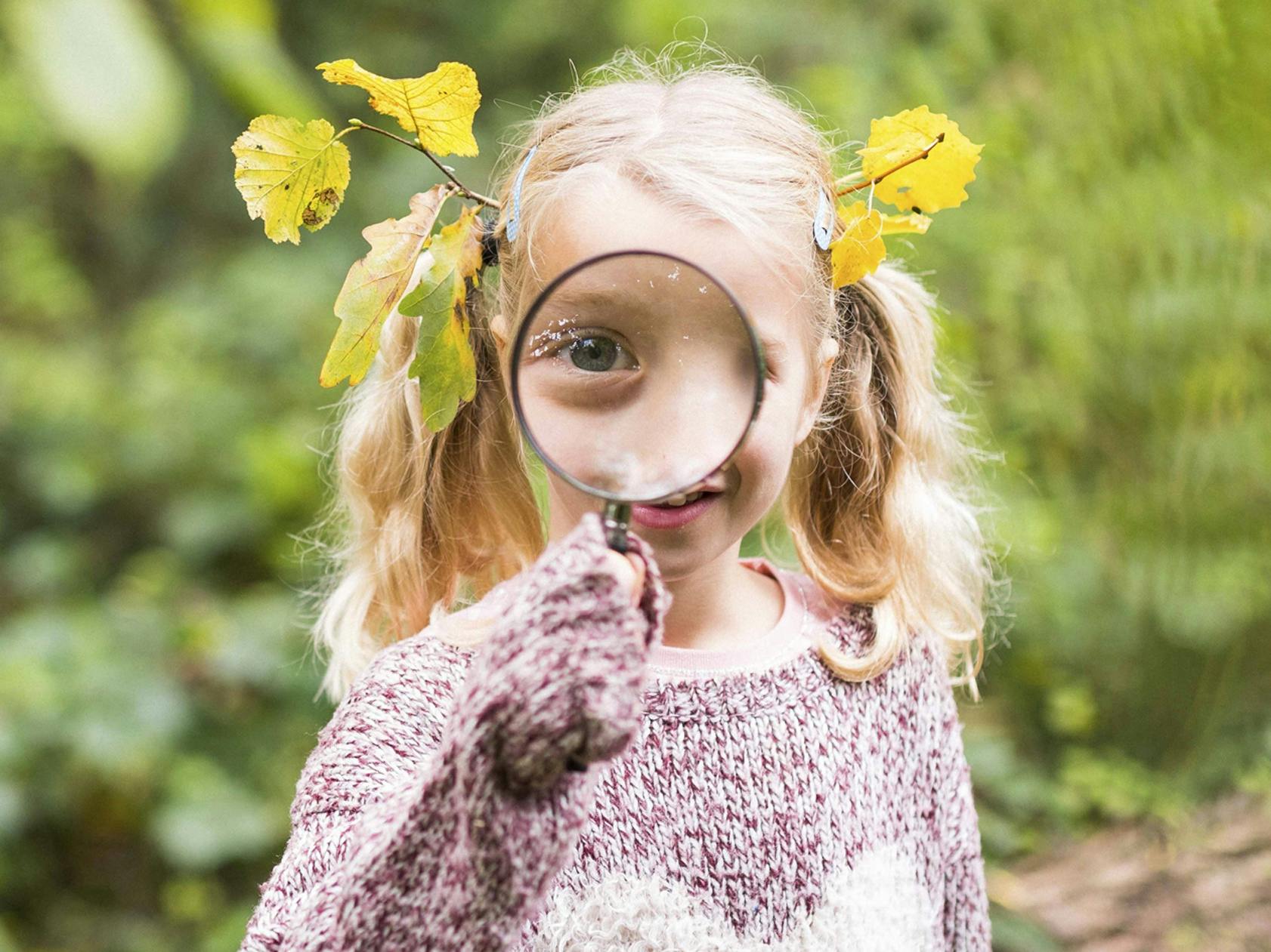 Photograph of girl with magnifying glass up close to her face