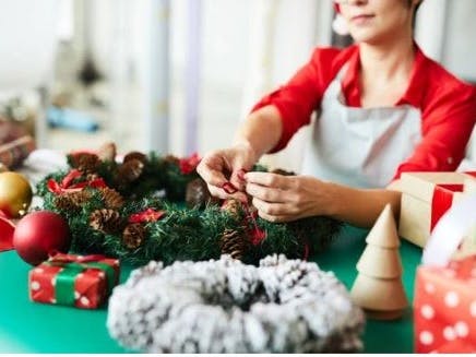 Photograph of a person in red and white putting the finishing touches to a wreath