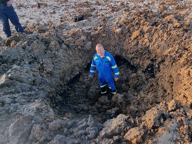 Selsey Coastguard Ashley Pledger in a crater caused by a controlled explosion of World War 2 ordinance at the Medmerry, Selsey courtesy of Selsey Coastguard Photograph of Selsey Coastguard Ashley Pledger in large crater caused by a controlled explosion of World War 2 ordinance at the Medmerry, Selsey courtesy of Selsey Coastguard