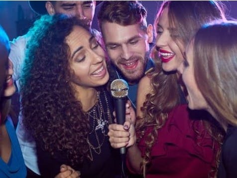 phtograph of several people singing into a microphone depicting karaoke