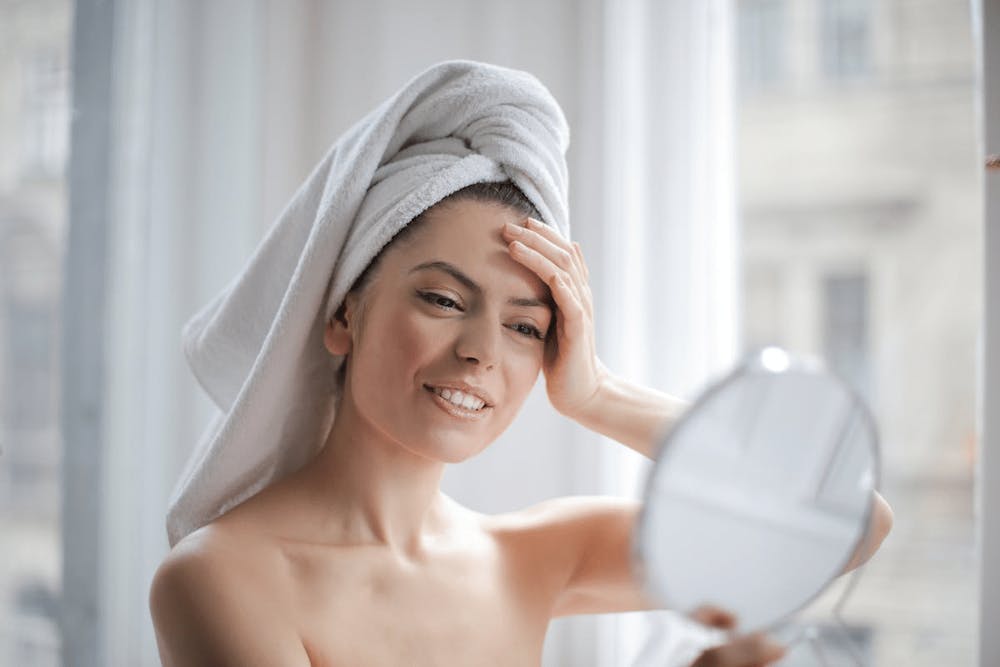 woman looking at herself in a handheld mirror
