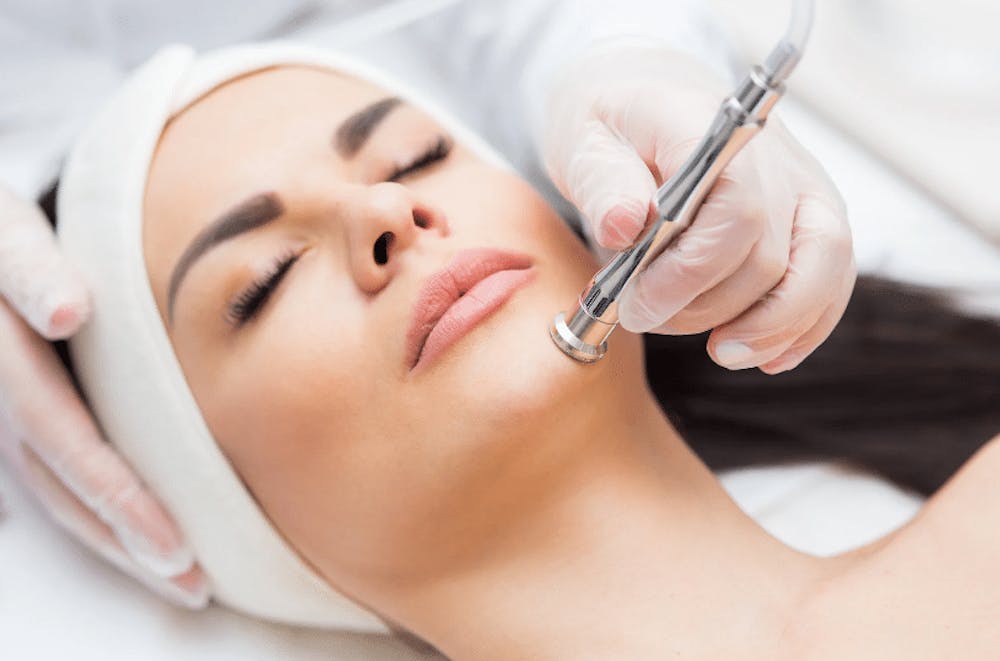 A woman receiving a skin care treatment with a high-tech device for facial rejuvenation, as part of a beauty treatment.