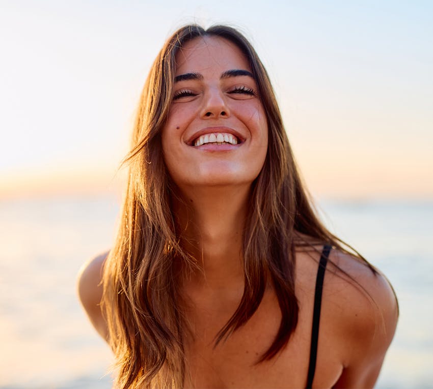 woman smiling infront of sunset