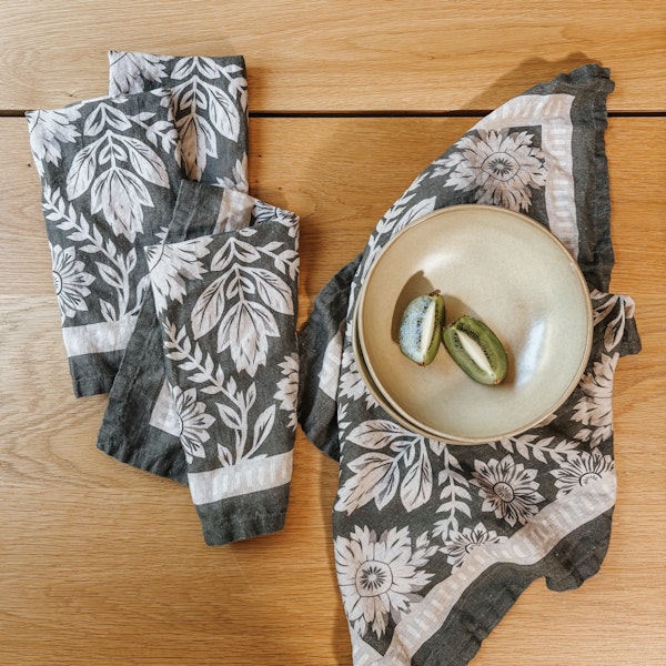 Gray floral linen napkins with a bowl on a wood table