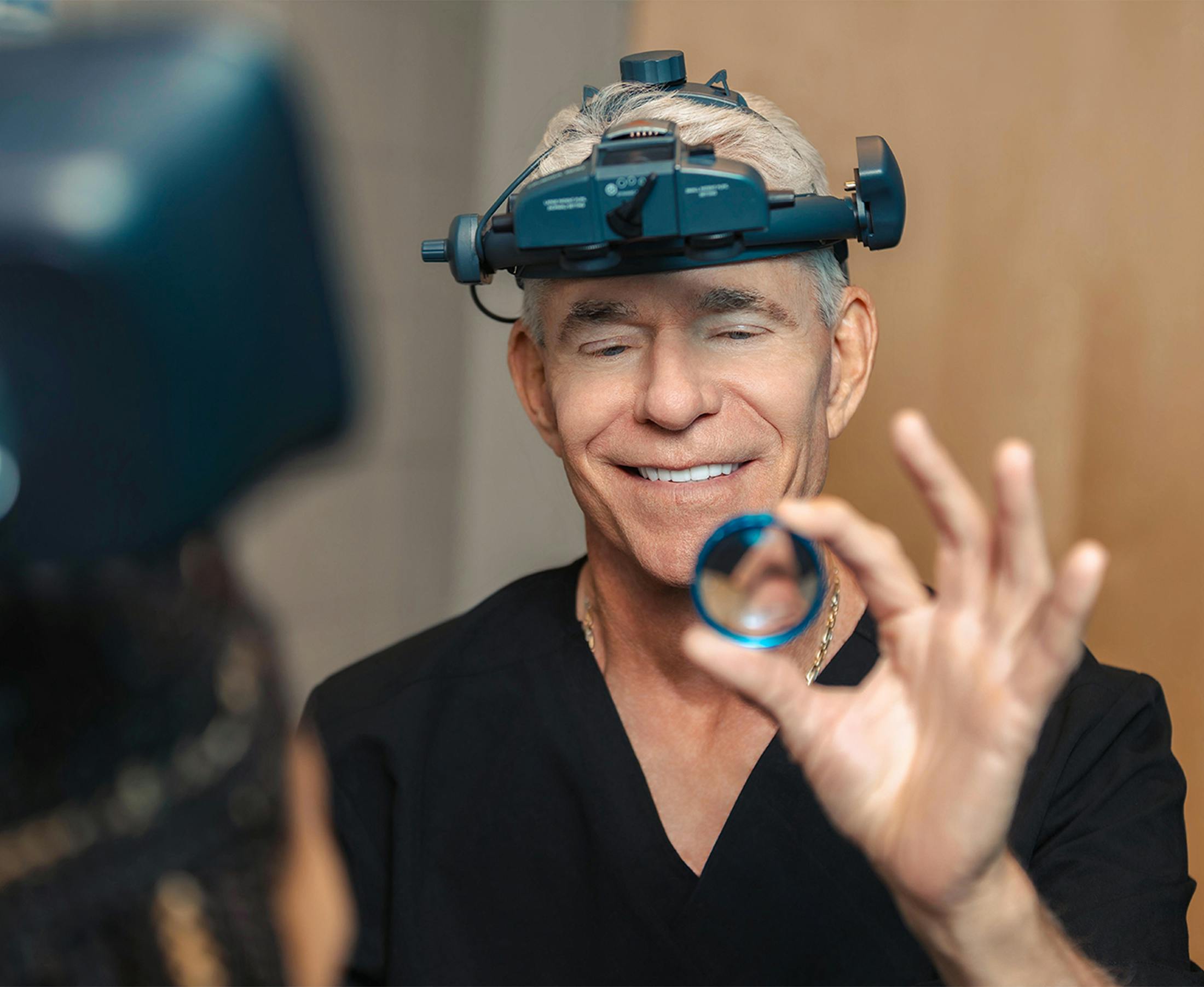 Surgeon holds intraocular lens while preparing for cataract surgery
