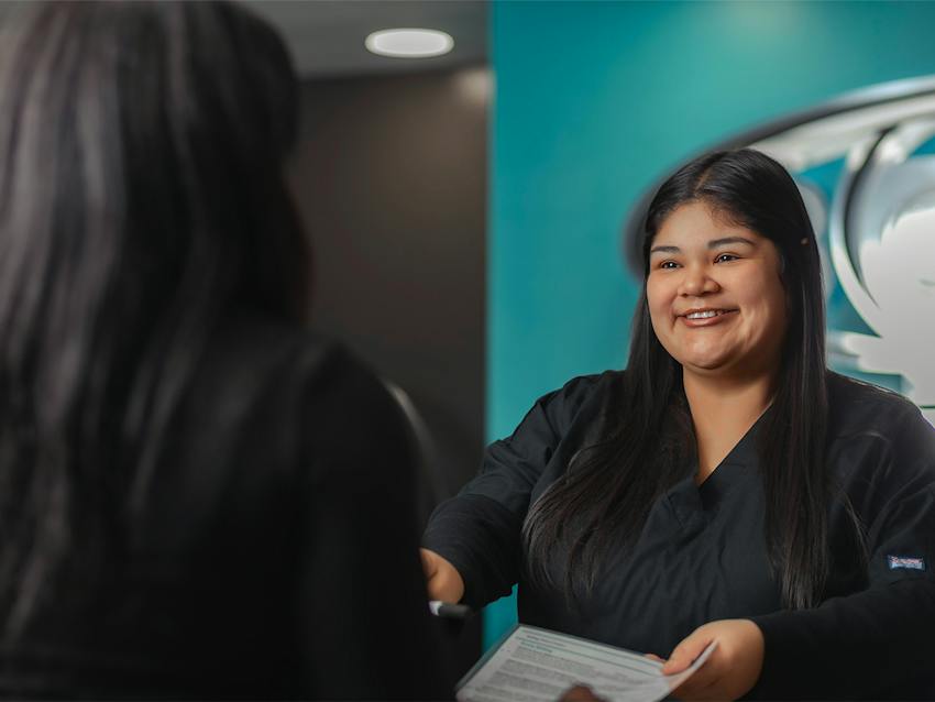 receptionist handing a paper to a patient