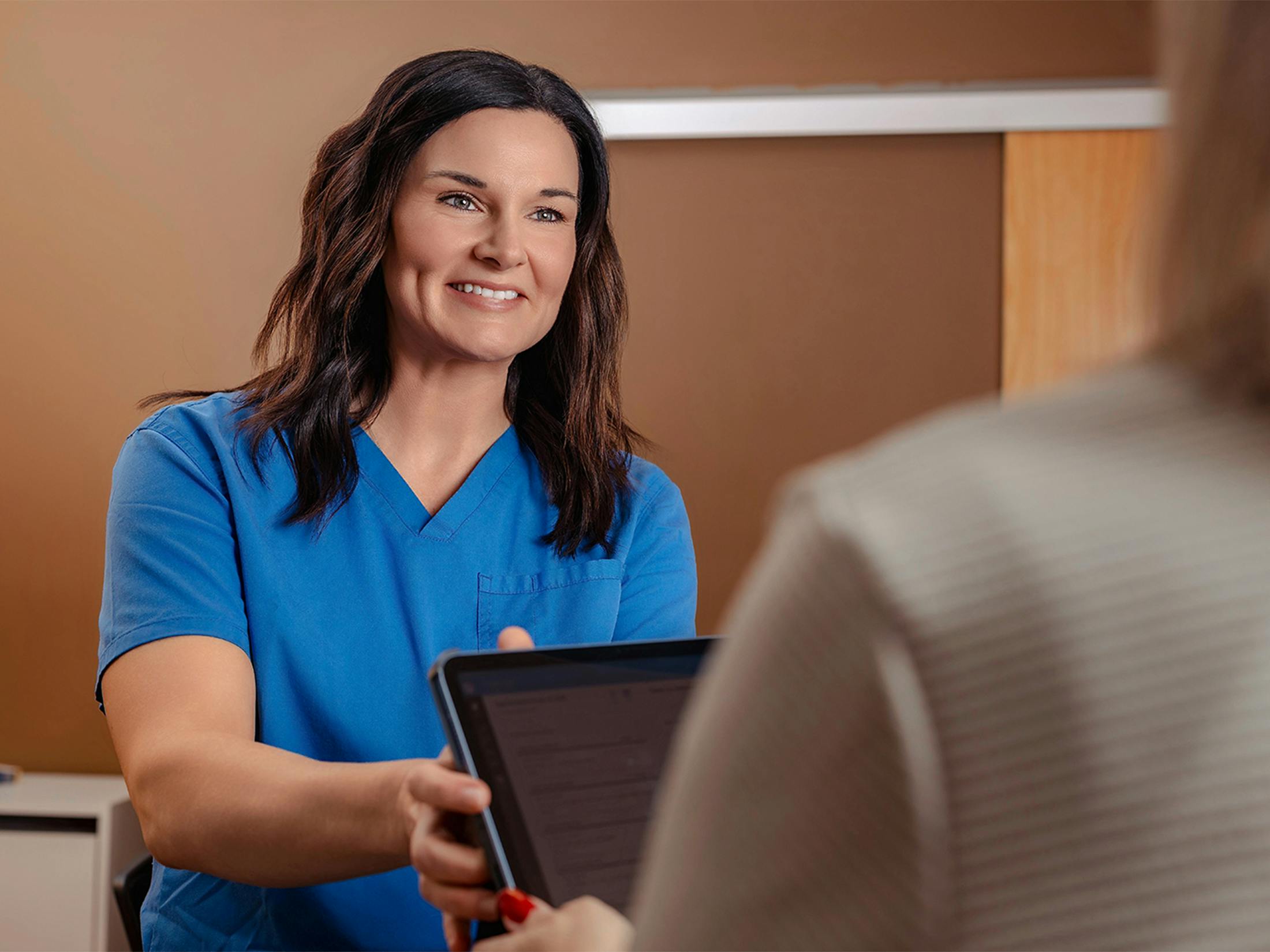 woman handing another woman a tablet