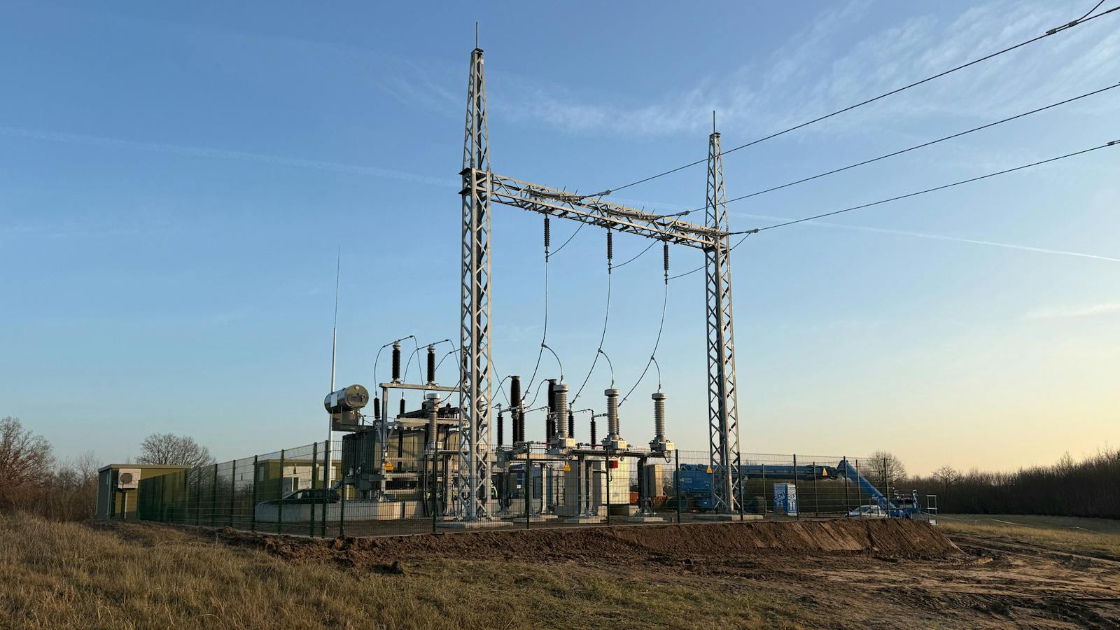 Umspannwerk mit Leistungstransformator, Hochspannungsschaltanlagen und Stahlgitterportal zur Anbindung an das Stromnetz über eine Freileitung.