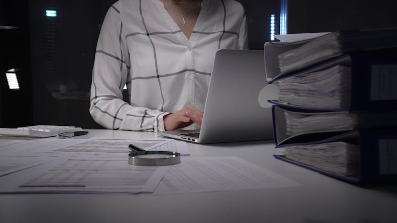 Person working at office desk late at night, typing on a laptop
