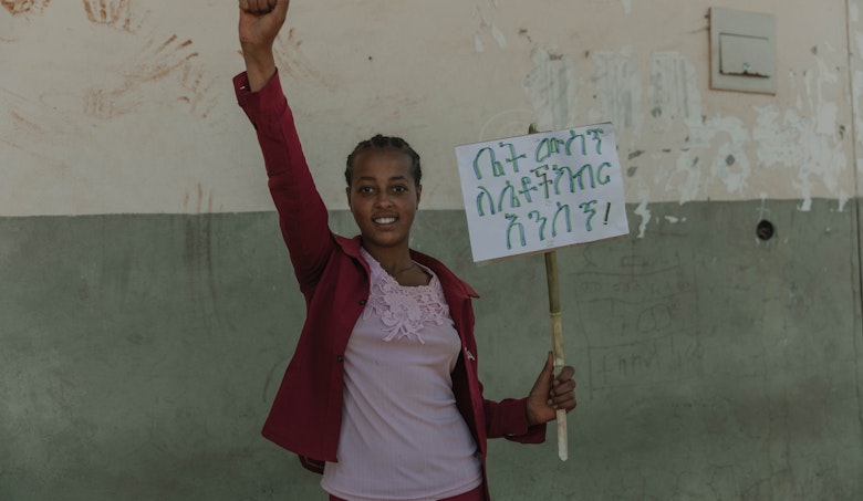 Kidist, holding a placard that reads, "Let's respect women at home."