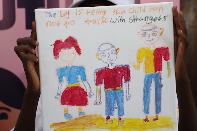 Child holding a drawing with a tip on online safety